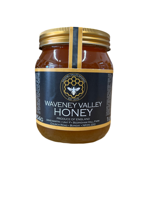 Jar of Waveney Valley Honey with a gold lid in a glass glass